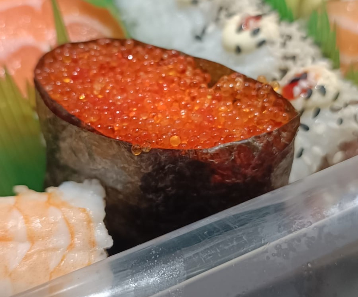 A box of sushi featuring a gunkan with tobiko (flying fish roe) topping.